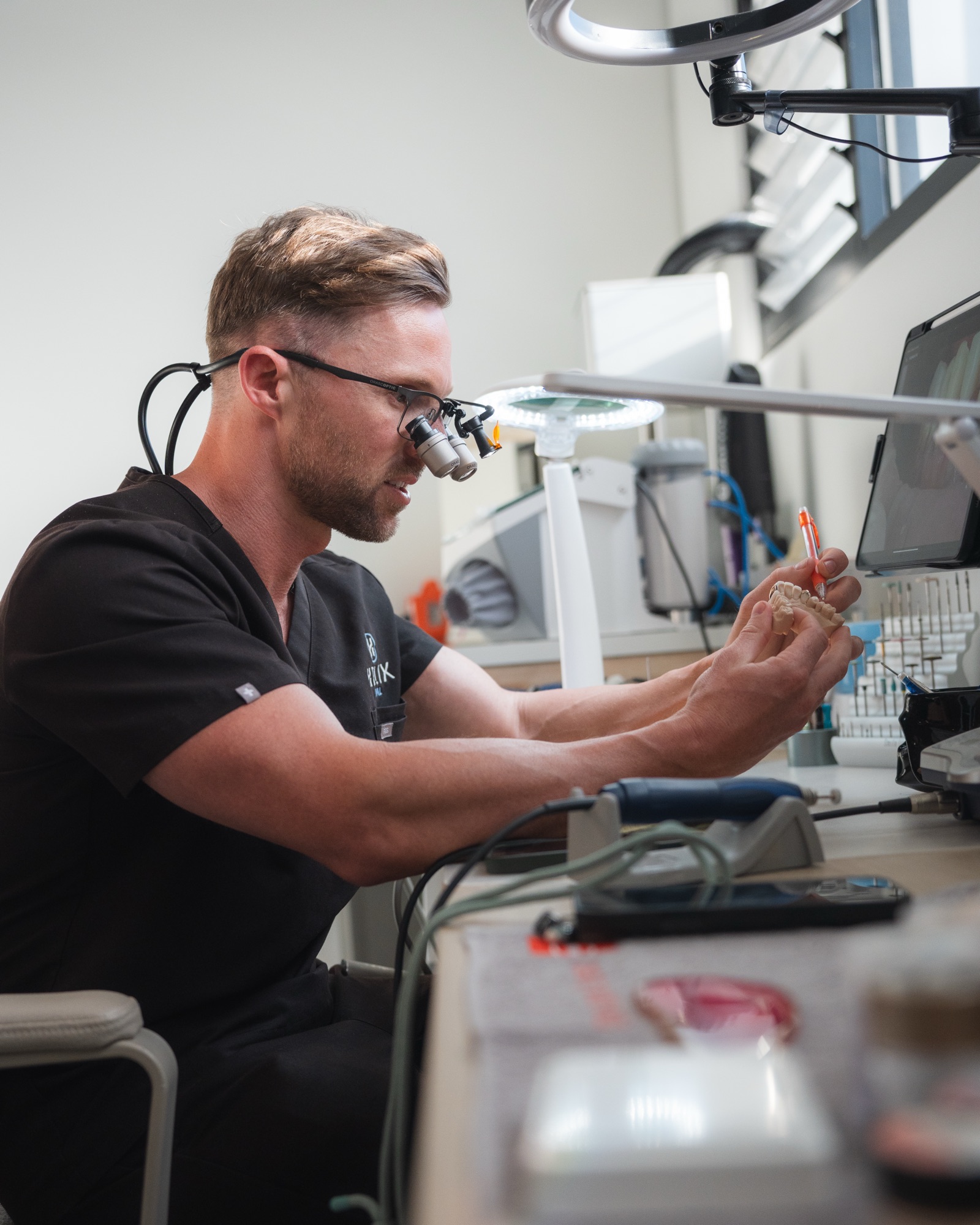 Dentist examining dental mould with loupes